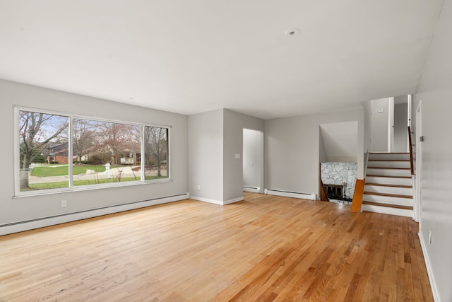 unfurnished living room with baseboards, a baseboard radiator, stairs, and wood finished floors