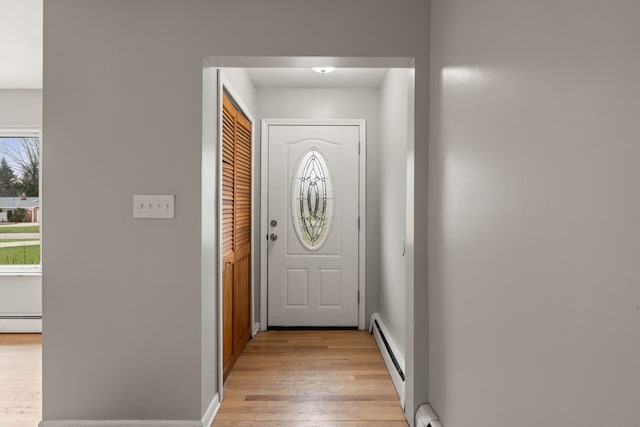 doorway to outside featuring baseboards, baseboard heating, a baseboard heating unit, and light wood-type flooring