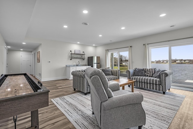 living room with light wood-style floors, baseboards, and recessed lighting