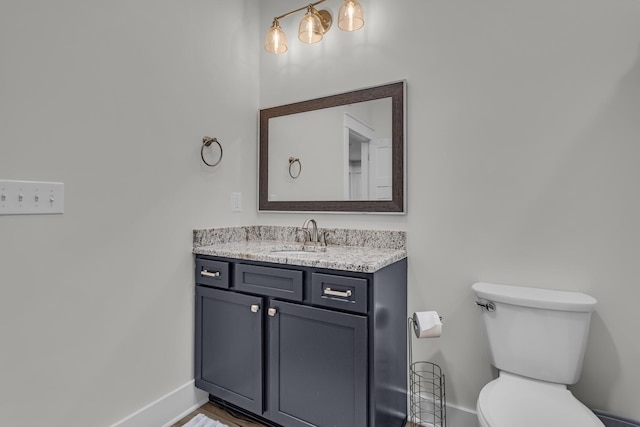 half bathroom featuring toilet, baseboards, and vanity