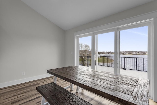 unfurnished dining area with baseboards, wood finished floors, and lofted ceiling
