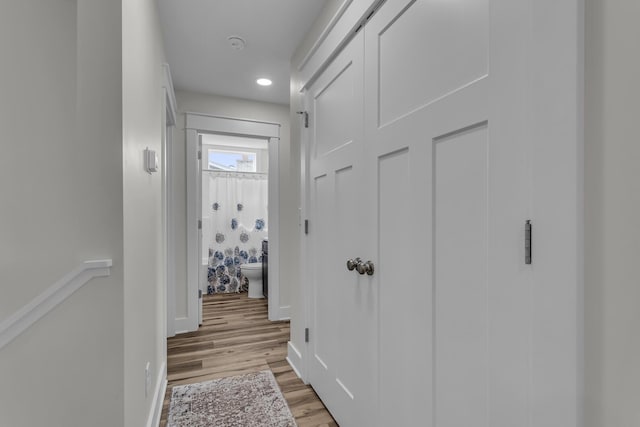 hall featuring light wood-style floors, recessed lighting, and baseboards