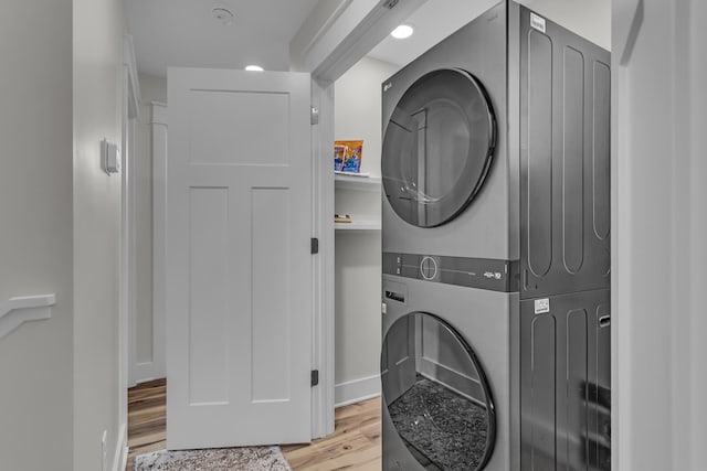 laundry room with light wood-type flooring, baseboards, laundry area, and stacked washer and dryer