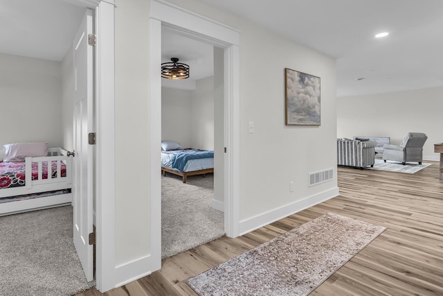 corridor featuring baseboards, recessed lighting, wood finished floors, and visible vents