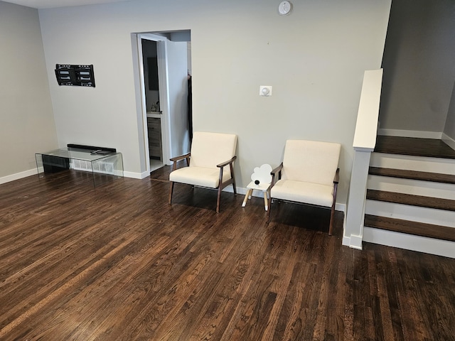living area with baseboards, wood finished floors, and stairway