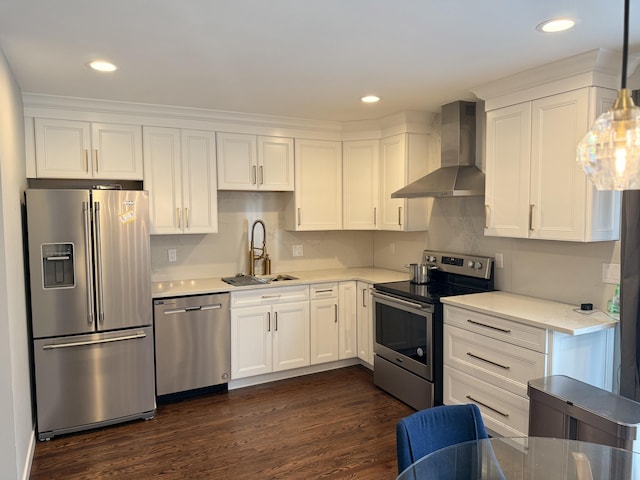 kitchen with wall chimney range hood, appliances with stainless steel finishes, a sink, light countertops, and white cabinetry
