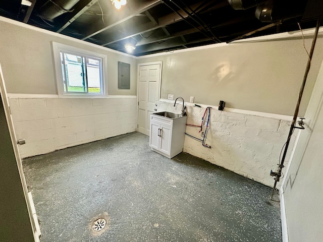 below grade area with a sink, concrete block wall, and electric panel