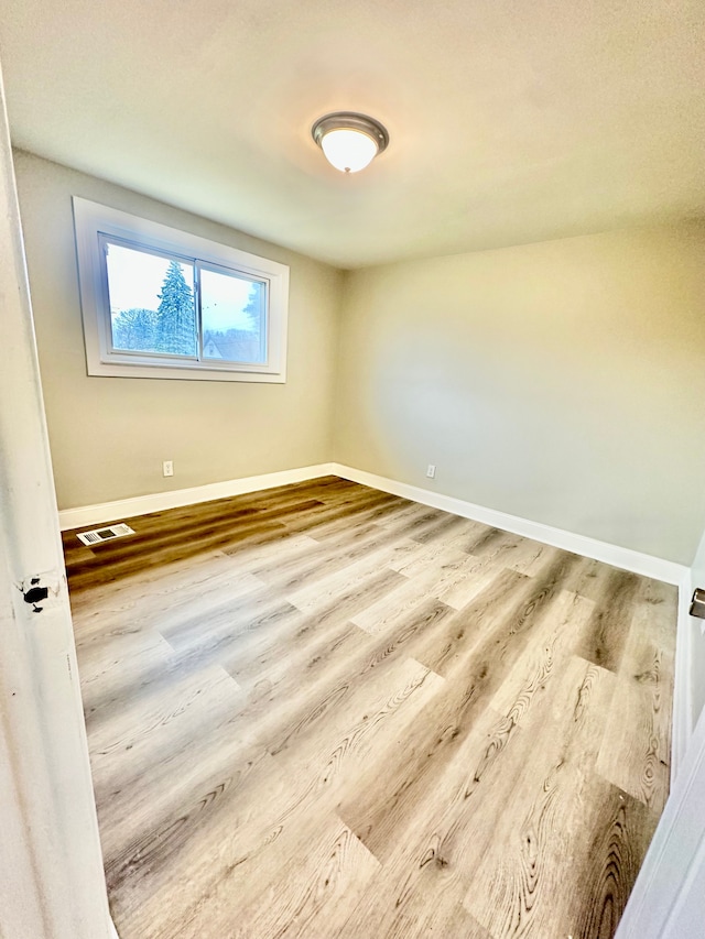 spare room with visible vents, baseboards, and wood finished floors