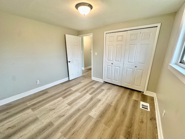unfurnished bedroom featuring a closet, visible vents, light wood-type flooring, and baseboards