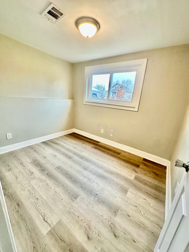spare room featuring visible vents, baseboards, and wood finished floors