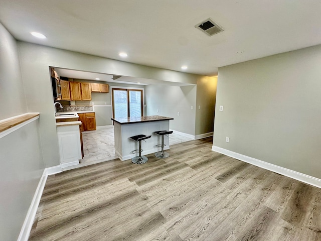kitchen featuring light wood-style flooring, a sink, visible vents, and recessed lighting
