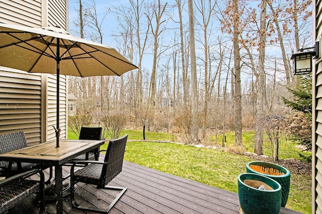 wooden deck featuring outdoor dining area and a lawn