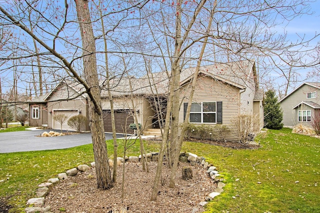 single story home featuring aphalt driveway, an attached garage, and a front lawn