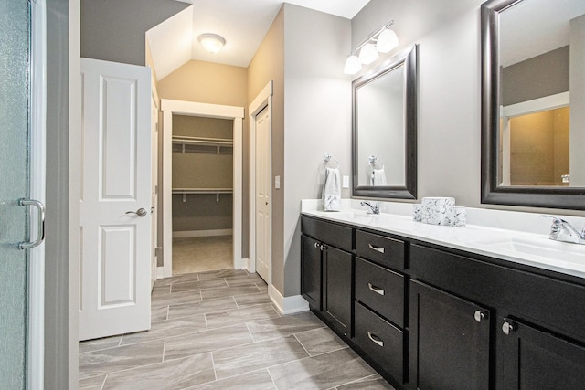 bathroom with a sink, a walk in closet, baseboards, and double vanity