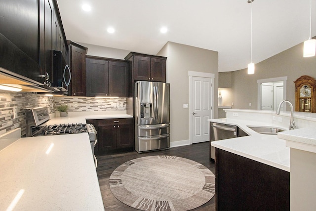 kitchen with light countertops, backsplash, dark wood-type flooring, appliances with stainless steel finishes, and a sink