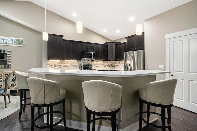 kitchen featuring light countertops, appliances with stainless steel finishes, dark wood-style floors, backsplash, and lofted ceiling