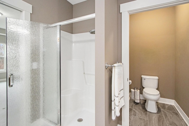 bathroom featuring a shower stall, baseboards, and toilet