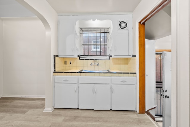 9233 Mckinney St, Detroit, MI 48224 - interior space featuring light wood-type flooring, decorative backsplash, tile counters, and white cabinetry