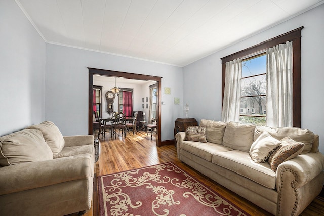 living area with a notable chandelier, ornamental molding, and wood-type flooring