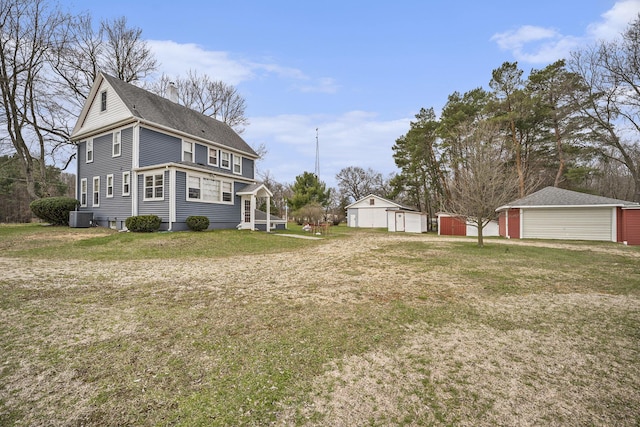 view of yard featuring an outdoor structure, a detached garage, and cooling unit