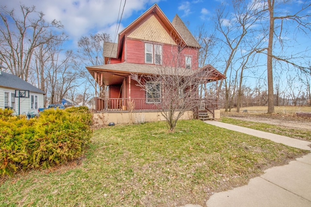 victorian house with a front yard, covered porch, and roof with shingles