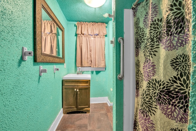 full bath with vanity, baseboards, curtained shower, a textured wall, and a textured ceiling