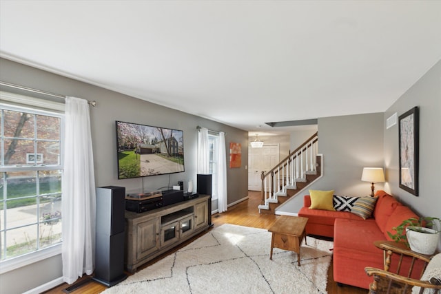 living area with stairs, visible vents, a healthy amount of sunlight, and light wood-style floors