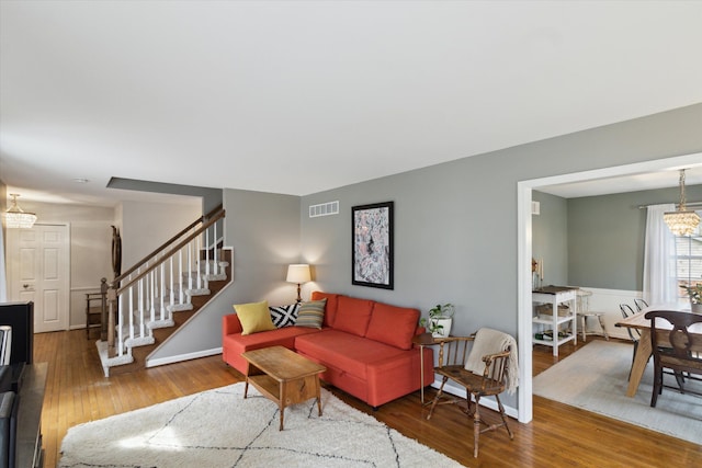 living area with visible vents, hardwood / wood-style flooring, a notable chandelier, and stairway