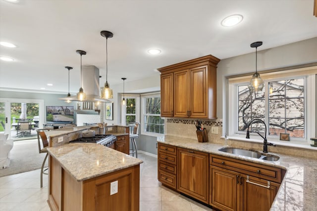 kitchen with light stone counters, a sink, brown cabinets, and plenty of natural light