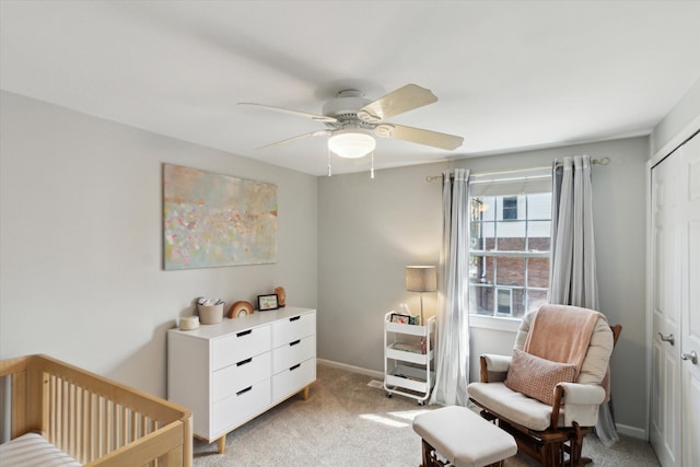 bedroom with light colored carpet, ceiling fan, a crib, and baseboards