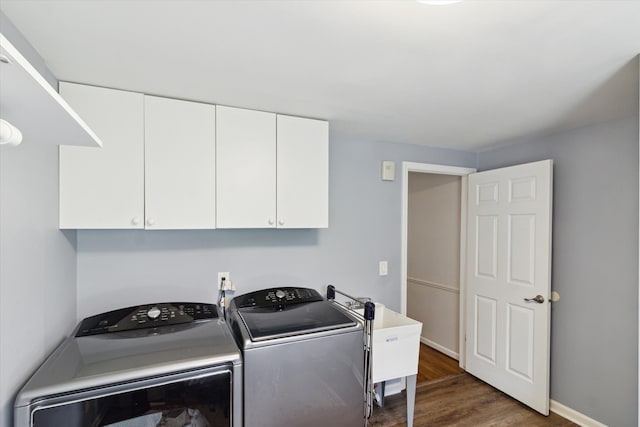 laundry area with a sink, washing machine and dryer, baseboards, cabinet space, and dark wood-type flooring