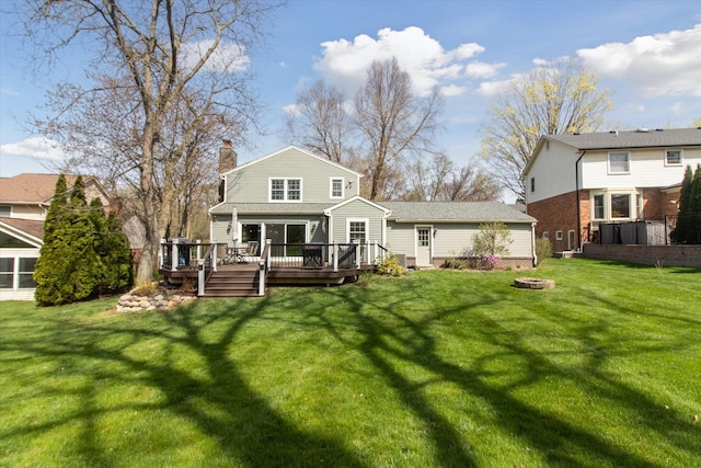 rear view of property with a yard, a deck, a chimney, and an outdoor fire pit