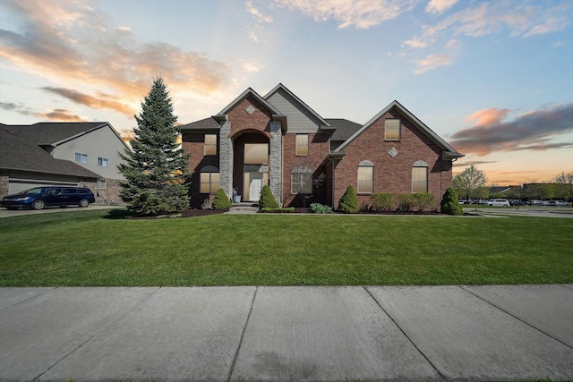 traditional-style home featuring a yard and brick siding