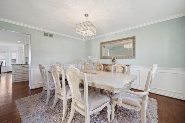 dining room with a wainscoted wall, dark wood-style floors, a chandelier, and visible vents