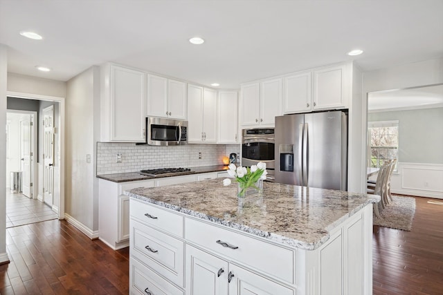 kitchen featuring white cabinetry, appliances with stainless steel finishes, dark wood-style floors, and light stone counters