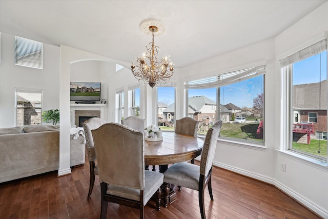 dining space featuring a notable chandelier, a wealth of natural light, and dark wood-type flooring
