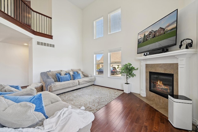 living room featuring visible vents, wood-type flooring, a towering ceiling, and a fireplace