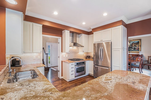 kitchen featuring light stone countertops, appliances with stainless steel finishes, a sink, white cabinetry, and wall chimney exhaust hood