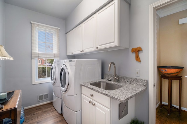 laundry room featuring dark wood-style floors, a sink, cabinet space, separate washer and dryer, and visible vents