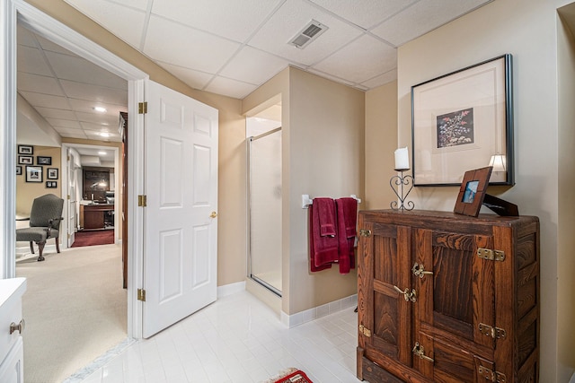 hall with baseboards, visible vents, light tile patterned floors, and a drop ceiling