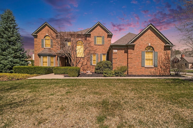 traditional-style home featuring a lawn and brick siding