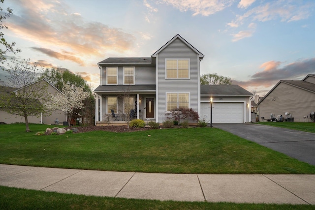 traditional home with a porch, an attached garage, a front yard, and aphalt driveway