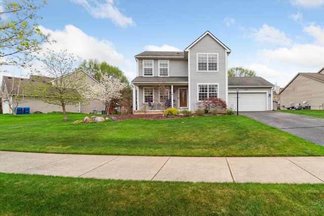 traditional-style house with a garage, a front lawn, aphalt driveway, and covered porch