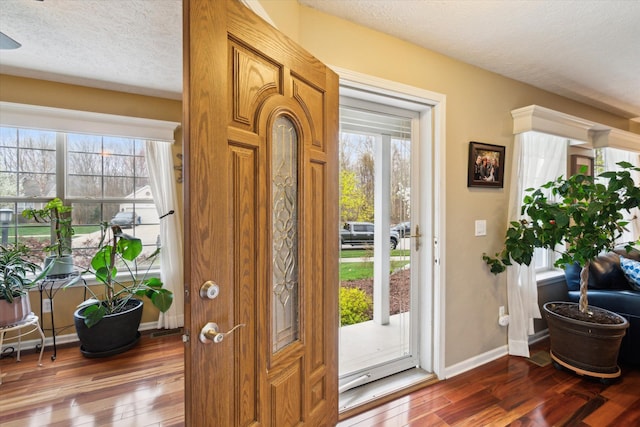 entryway featuring wood-type flooring, a textured ceiling, and baseboards