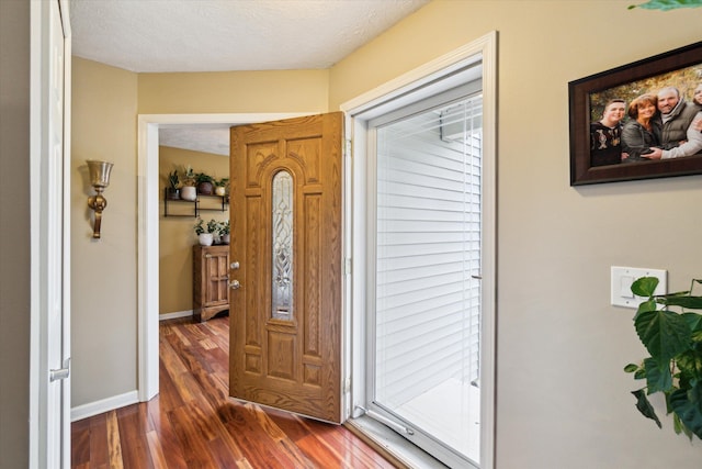 entryway with dark wood-style flooring, baseboards, a wealth of natural light, and a textured ceiling