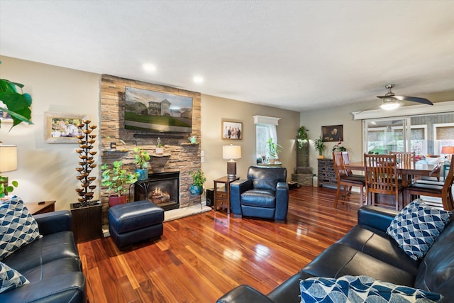 living room with a fireplace, plenty of natural light, wood-type flooring, and a ceiling fan