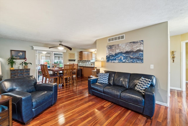 living area featuring visible vents, baseboards, ceiling fan, and wood finished floors