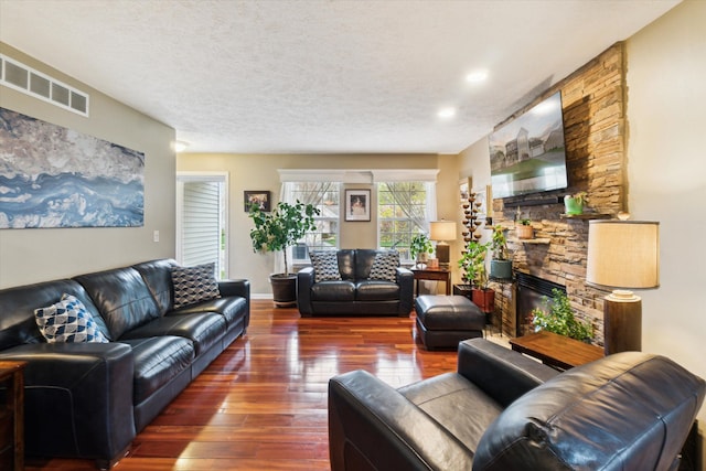 living area with visible vents, recessed lighting, a stone fireplace, and hardwood / wood-style floors