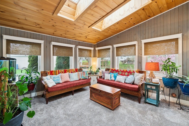 sunroom / solarium with wooden walls, carpet, and lofted ceiling with skylight