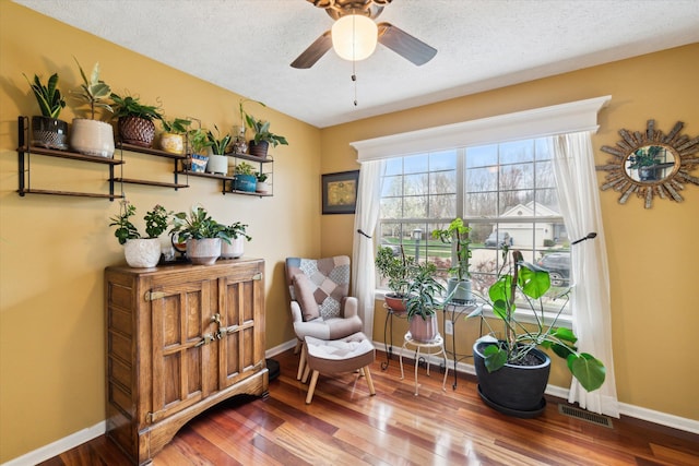 living area with visible vents, baseboards, ceiling fan, and wood finished floors